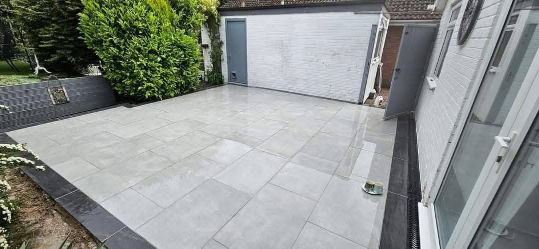 Grey porcelain patio with a dark border outside a garden room
