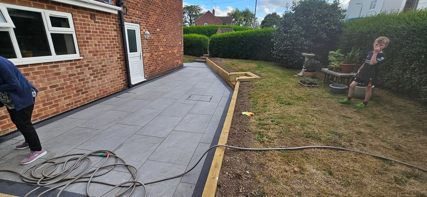 Grey porcelain side path being installed beside a lawn