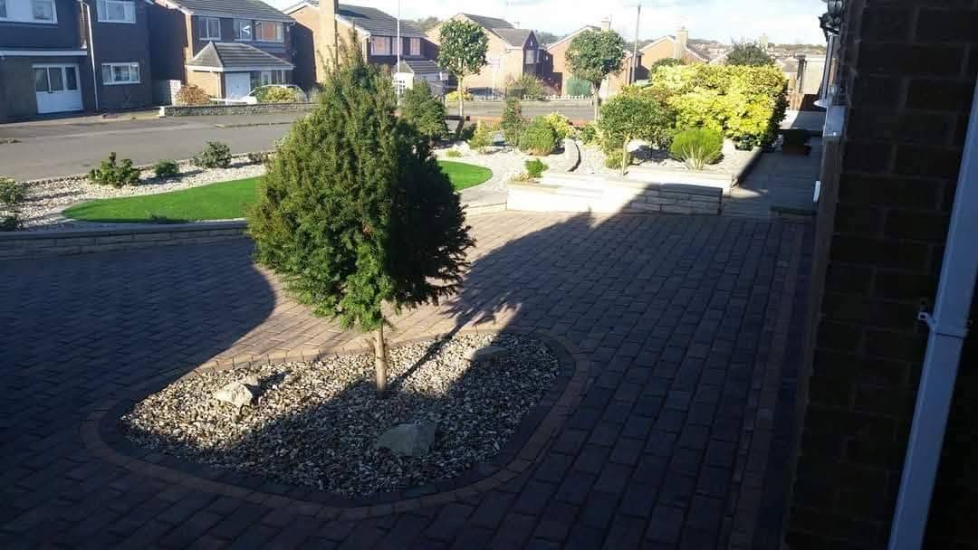 Block paving driveway with a circular gravel bed and tree