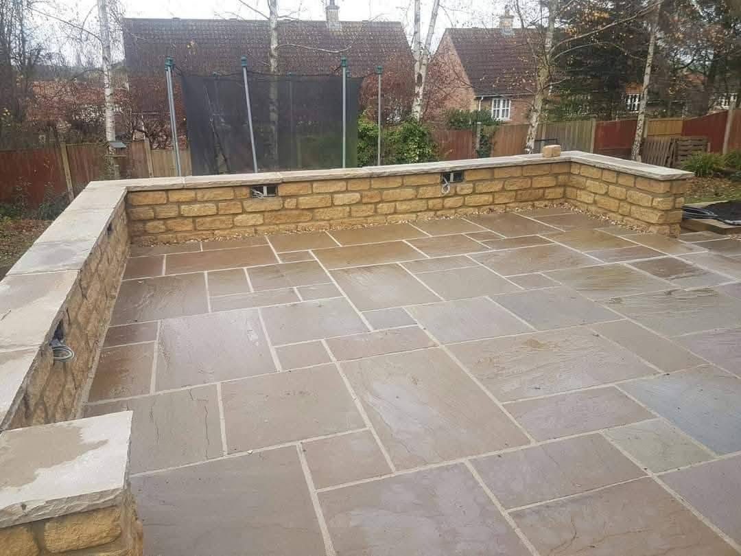 Indian stone patio enclosed by buff stone walling