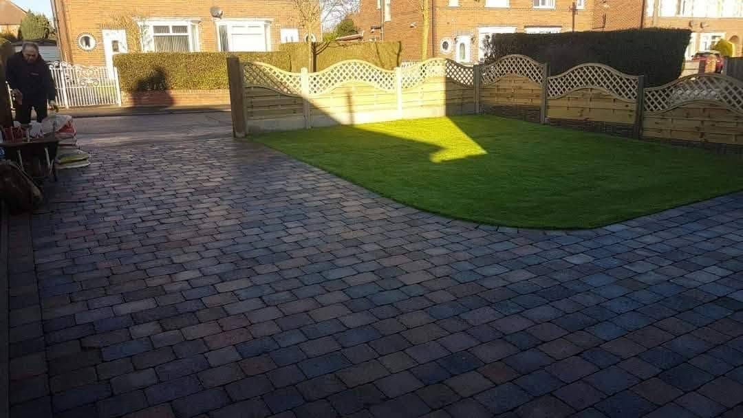 Dark block paving driveway curving around a front lawn