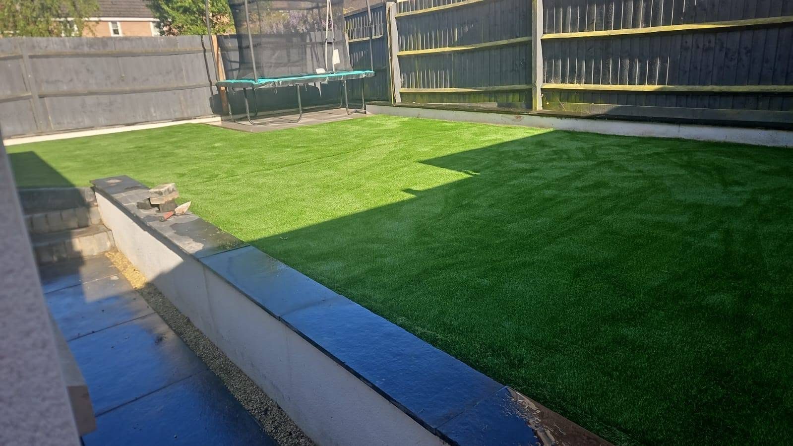 Artificial grass lawn below a raised patio