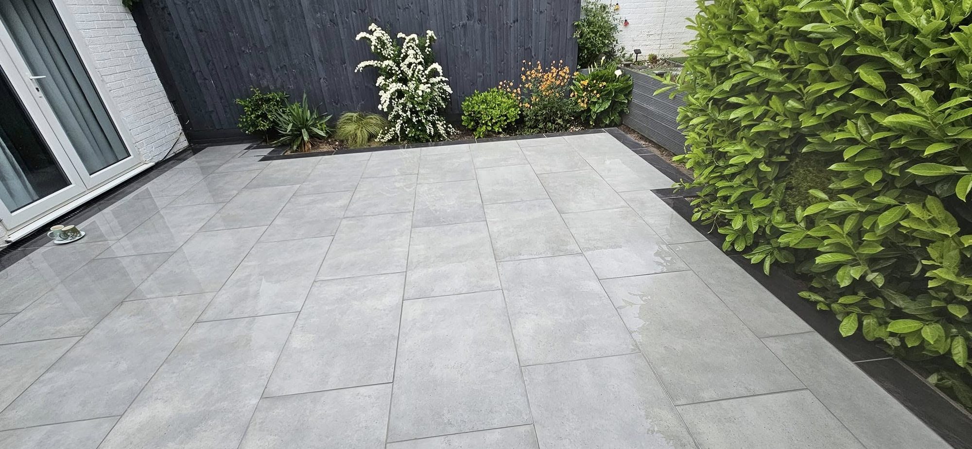 Grey porcelain patio with a dark border and planting