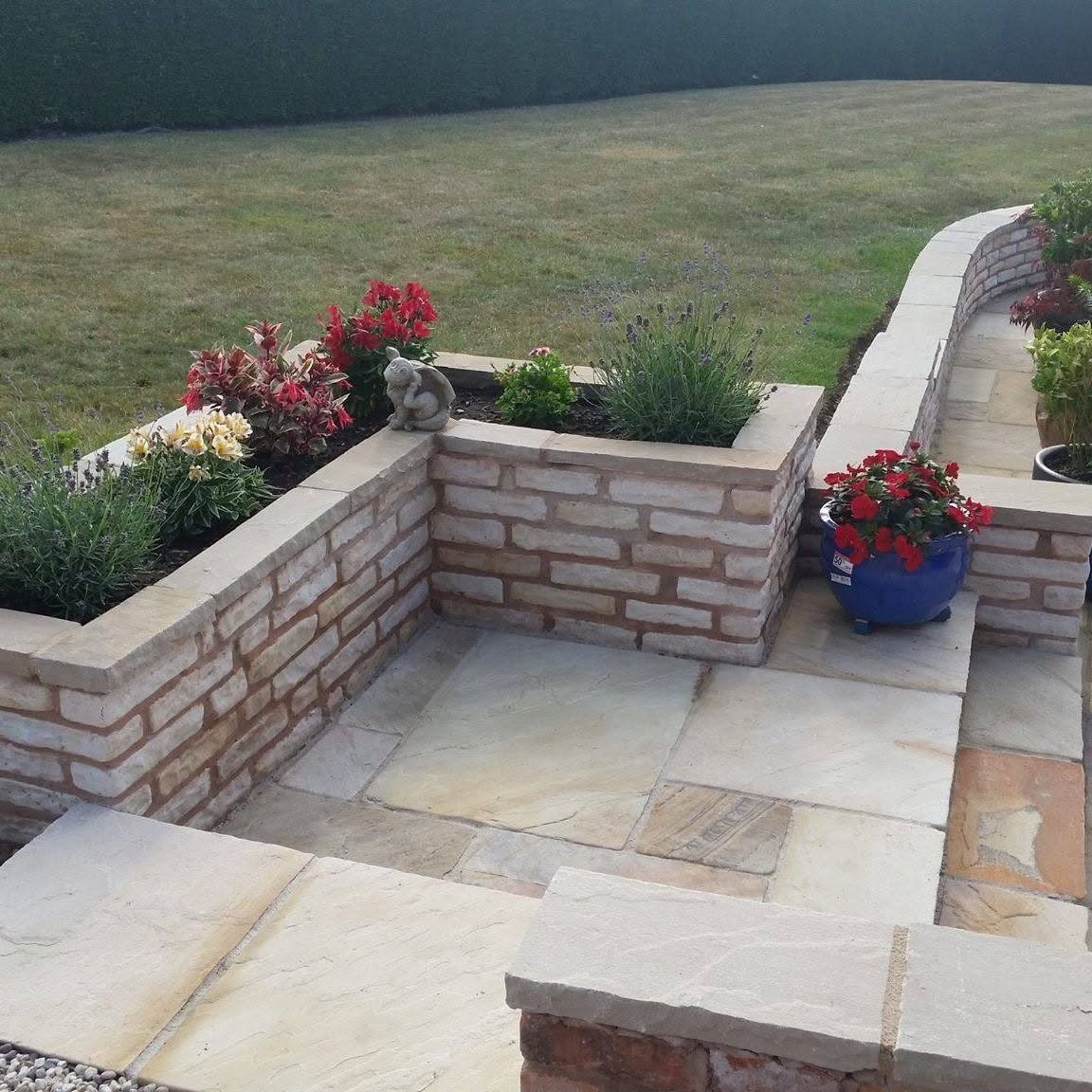 Natural stone patio with raised stone planting beds and colourful flowers