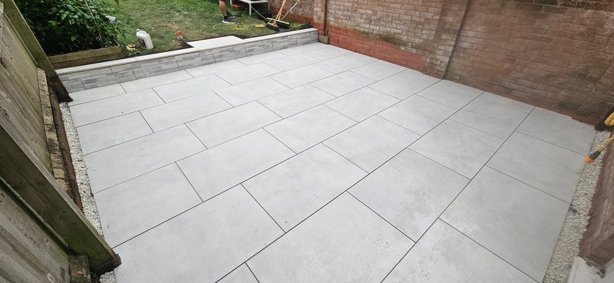Light grey porcelain patio against a brick wall