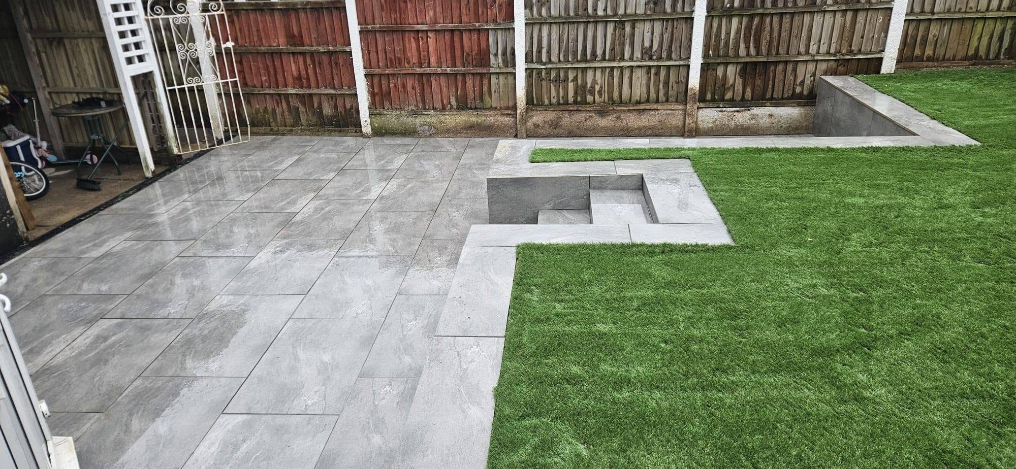 Grey porcelain patio with steps up to an artificial grass lawn
