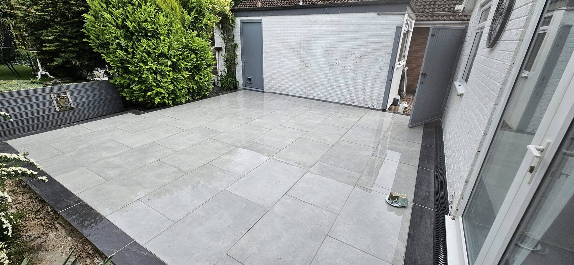 Grey porcelain patio beside a garden room