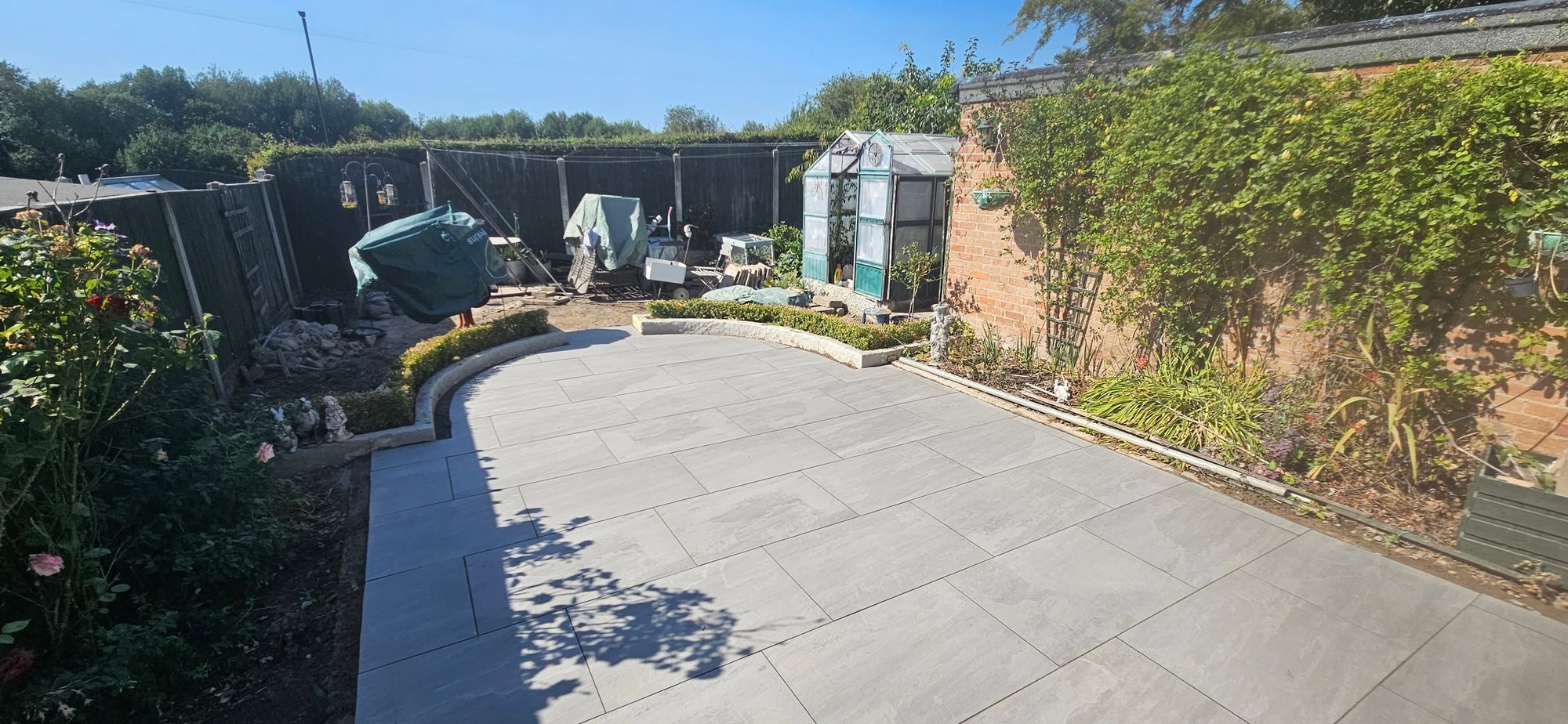 Grey porcelain patio with a curved edge in a back garden